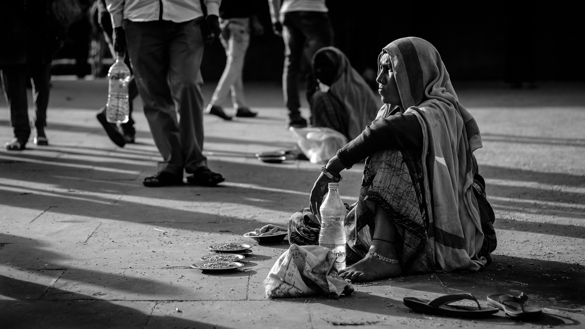 A black-and-white documentary scene showing a woman working on a city street