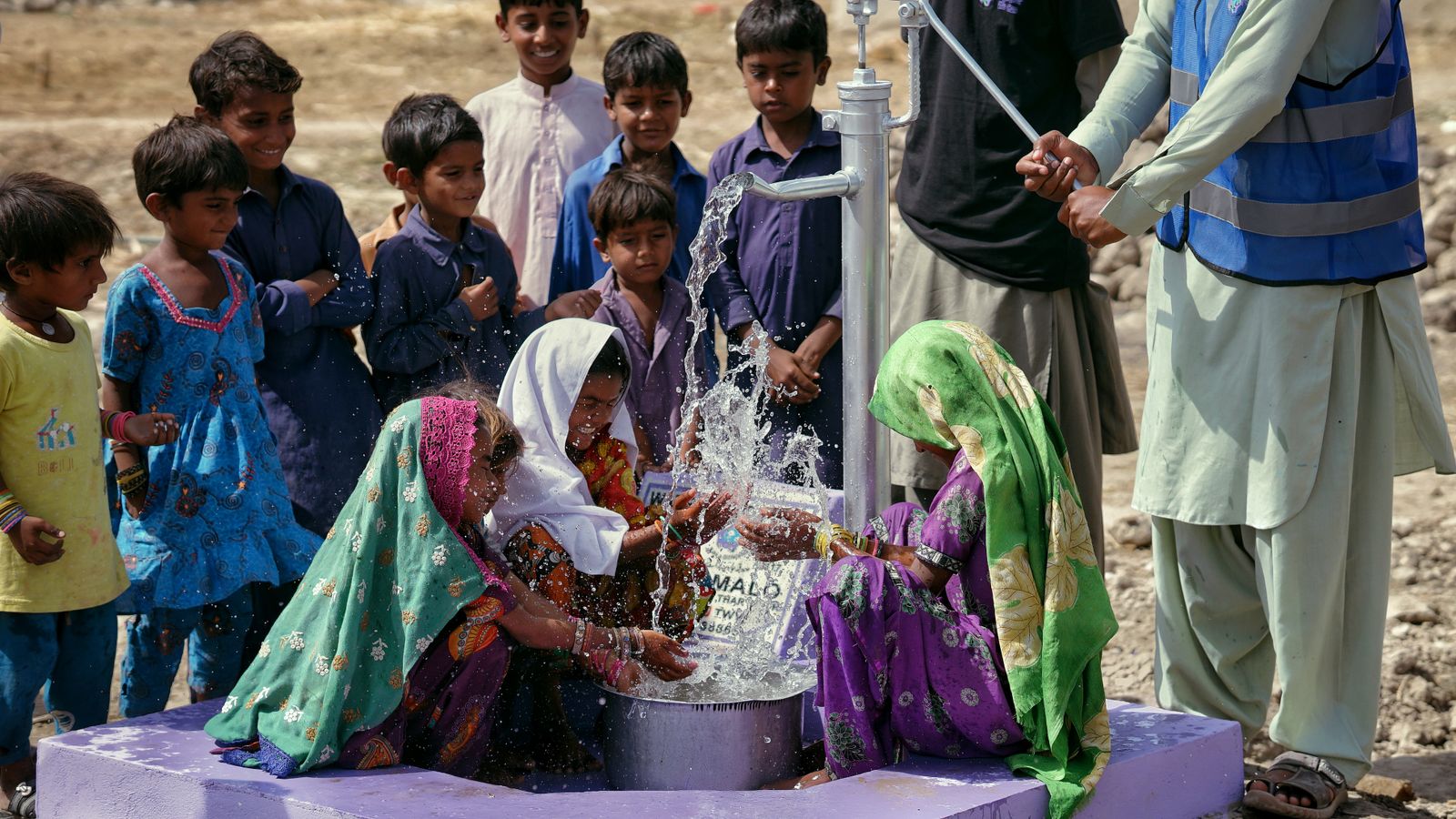 Children gathering around a clean-water hand pump